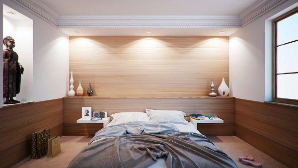 Une chambre avec un lit avec draps gris et un mur en bois