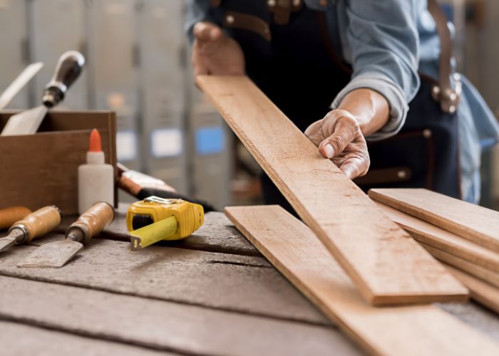 artisan tient une planche d'une maison