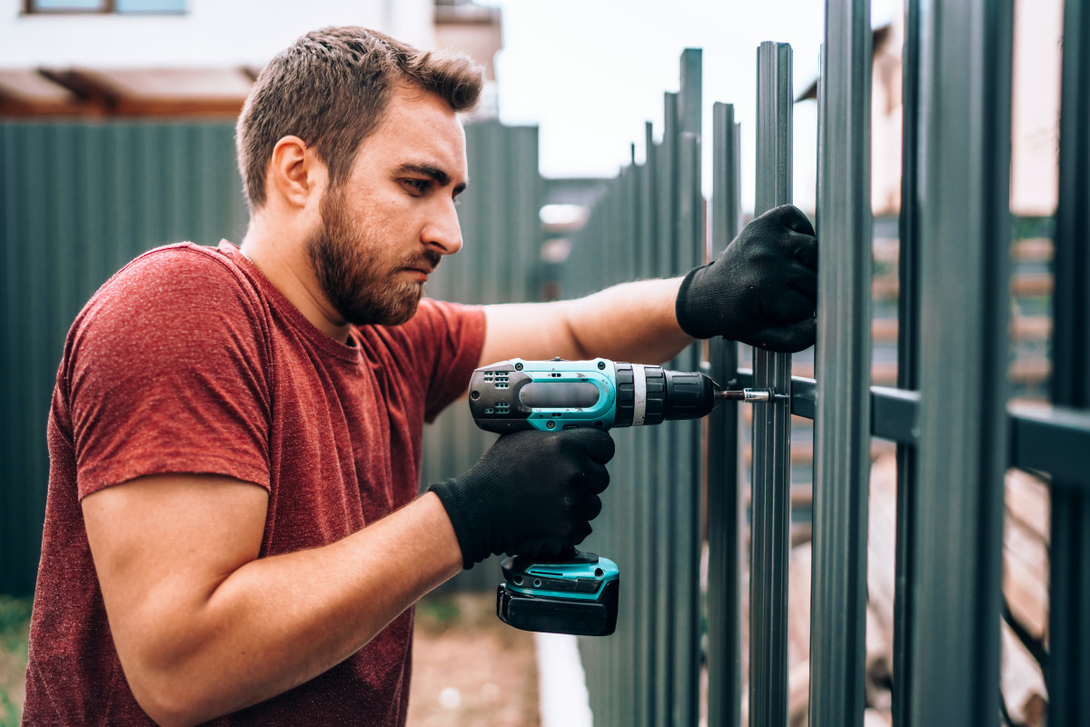 homme faisant la rénovation d'une cloture